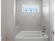 Bathroom bathtub area featuring tile surround, window, shower head, and bench seat at 108 Stanton Estates Cir, Winter Garden, FL 34787
