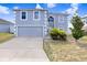 Two-story home featuring blue stucco exterior, two-car garage, and concrete driveway, set against a blue sky at 125 Vervain Ave, Davenport, FL 33837