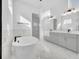 Bright bathroom with a soaking tub, gray double-sink vanity, and marble tile floors at 13081 Sunrise Harvest Dr, Winter Garden, FL 34787