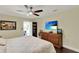 Bedroom showcases a ceiling fan, wooden dresser with television, and view to an enclosed porch at 1390 Yellow Pine Ct, Winter Springs, FL 32708