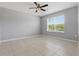 Light-filled bedroom with tile flooring, neutral colors, and a ceiling fan at 15250 Aquarius Way, Mascotte, FL 34753