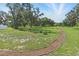 A peaceful community green space featuring mature trees and a winding mulch path for leisurely walks at 15250 Aquarius Way, Mascotte, FL 34753