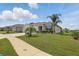 Lovely single-Gathering home showcasing a verdant lawn, mature palm trees, and a cozy facade at 15250 Aquarius Way, Mascotte, FL 34753