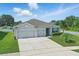 Charming home with a two-car garage, lush green lawn, and neatly trimmed landscaping at 15250 Aquarius Way, Mascotte, FL 34753