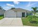 Beautiful single-story home featuring a well-manicured lawn, two-car garage, and inviting entryway at 15250 Aquarius Way, Mascotte, FL 34753