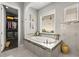Luxurious bathroom featuring a soaking tub with tile surround and a view into the organized walk-in closet at 16761 Broadwater Ave, Winter Garden, FL 34787