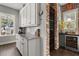 Gourmet kitchen featuring white cabinetry, marble countertops, and a wine fridge with a brick wall feature at 16761 Broadwater Ave, Winter Garden, FL 34787