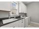 Laundry room with granite countertops, white cabinets, stainless steel sink, and modern washer/dryer at 16761 Broadwater Ave, Winter Garden, FL 34787