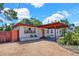 Single-story home with a gravel driveway and covered carport, under a partly cloudy blue sky at 1705 Virginia Dr, Orlando, FL 32803