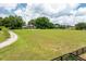Extensive backyard featuring a vast green field, mature trees, and a view of the elegant brick house at 17524 Seidner Rd, Winter Garden, FL 34787