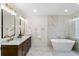 Modern bathroom featuring double sinks, marble countertops, and a luxurious soaking tub at 17524 Seidner Rd, Winter Garden, FL 34787