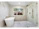 Serene bathroom featuring a standalone tub, frameless shower, and a window with garden views at 17524 Seidner Rd, Winter Garden, FL 34787