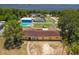 Aerial view of a yellow home with pool and partial lake view with green trees at 181 W Minnehaha Ave, Clermont, FL 34711