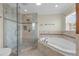 Beautiful bathroom featuring a glass shower enclosure, soaking tub, and travertine tile at 181 W Minnehaha Ave, Clermont, FL 34711