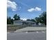 Single story home with a gray roof, a front yard with trees and bushes under a sunny sky at 2233 N Normandy Blvd, Deltona, FL 32725