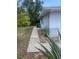 A concrete pathway leads along the side yard of a house with green foliage and a glimpse of a utility box at 2233 N Normandy Blvd, Deltona, FL 32725