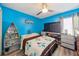Bedroom featuring bright blue walls, ceiling fan, and playful decor at 2354 Barons Ct, Tavares, FL 32778