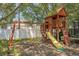 Wooden backyard playset with swings, slide, and climbing wall surrounded by mature trees and lush landscaping at 2354 Barons Ct, Tavares, FL 32778