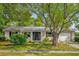 Charming single-story home with a manicured lawn, a metal roof, an attached garage, and mature trees at 2357 E Dana Dr, Deltona, FL 32738