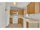 Functional kitchen with wooden cabinets, white appliances, tile flooring, and a sunlit window at 250 Hickory Ave, Orange City, FL 32763