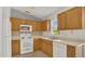 Well-lit kitchen with white appliances, wood cabinets, and a tiled backsplash, offering a functional space at 250 Hickory Ave, Orange City, FL 32763