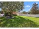 Large back yard with lush green grass, mature tree, partial fence, and view of rear exterior of the home at 2762 Pepper Ln, Orlando, FL 32812