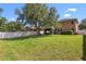 Spacious green backyard features a large shade tree, a white fence, and the rear exterior of the home at 2762 Pepper Ln, Orlando, FL 32812