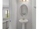 A compact half bath featuring a pedestal sink with gold fixtures and an oval mirror at 341 Burma St, Kissimmee, FL 34747