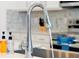 Close up of a modern chrome kitchen faucet and sink with white countertops and mosaic backsplash at 3860 Sonoma Blvd, Kissimmee, FL 34741