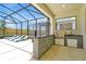Screened-in outdoor kitchen area with stainless steel grill and bar overlooking the pool and backyard at 3860 Sonoma Blvd, Kissimmee, FL 34741