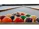 Close-up of billiard balls racked on a pool table with cues in the background, ready for a game at 3860 Sonoma Blvd, Kissimmee, FL 34741