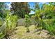 Lush backyard featuring diverse plantings, offering a private and serene outdoor space, enclosed by a white fence at 4571 Abaco Dr, Tavares, FL 32778