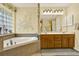 This bathroom features a large tub, neutral tile, and double sinks with wood cabinets at 4571 Abaco Dr, Tavares, FL 32778