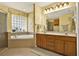Bright bathroom features a jacuzzi tub beneath a glass block window, plus double sinks with wood cabinetry at 4571 Abaco Dr, Tavares, FL 32778