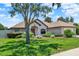Well-maintained single-story home with mature trees, lush lawn, and colorful landscaping at 4571 Abaco Dr, Tavares, FL 32778