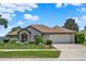 Charming single-story home with lush landscaping, a brick driveway, and an attached two-car garage at 4571 Abaco Dr, Tavares, FL 32778