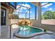 A luxurious built-in hot tub featuring a rock waterfall and surrounded by tile in a screened enclosure at 4571 Abaco Dr, Tavares, FL 32778