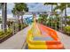Colorful waterslide with yellow and orange sections, surrounded by palm trees and lush vegetation at 640 Lasso Dr, Kissimmee, FL 34747