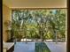 Enjoy the serenity of this balcony boasting glass railings, cozy seating, and a view of lush green trees and sunlight at 7667 Recife Dr, Kissimmee, FL 34747
