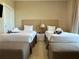 Comfortable bedroom with two twin beds, soft neutral colors, and bedside table at 7667 Recife Dr, Kissimmee, FL 34747