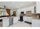 A well lit kitchen boasts white cabinetry, marble countertops, and stainless steel appliances next to a cozy living area at 802 Kaywood Dr, Orlando, FL 32825