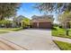 Impressive home exterior featuring a well manicured lawn, mature trees, and a spacious driveway and three-car garage at 8312 Prestbury Dr, Orlando, FL 32832