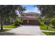 A well-maintained two-story house with a tile roof, a brick driveway, a two-car garage, and nice landscaping at 8312 Prestbury Dr, Orlando, FL 32832