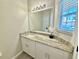 Bathroom with granite countertop vanity, white cabinets, large mirror and natural light from window at 944 Park Terrace Cir, Kissimmee, FL 34746