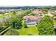 An aerial view captures the home's tile roof and screened in pool, surrounded by lush landscaping and a serene pond at 10352 Burris Ct, Orlando, FL 32836