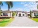 Charming front exterior view featuring a paver driveway, lush flowerbeds, and arched entryway at 10352 Burris Ct, Orlando, FL 32836