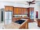 Kitchen featuring wood cabinets, granite countertops, a center island with cooktop, and stainless steel appliances at 10352 Burris Ct, Orlando, FL 32836