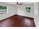 Bright bedroom featuring hardwood floors, white walls, a ceiling fan, and natural light from two windows at 14837 Sussex Dr, Orlando, FL 32826