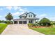 Beautiful home with a well-manicured lawn, mature trees, a three-car garage, and a welcoming front porch at 15208 Lake Claire Overlook Dr, Winter Garden, FL 34787