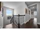 Well-lit hallway with dark hardwood floors, decorative railings, and scenic views from the staircase window at 15208 Lake Claire Overlook Dr, Winter Garden, FL 34787